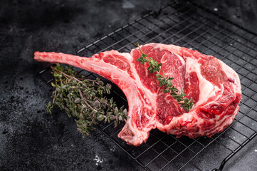 Uncooked tomahawk steak, raw black angus beef rib eye with bone. black background. top view © Mironov