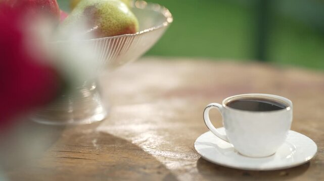 A cup of coffee and a bowl of fresh fruits.  A cup with black (Eastern) coffee on a sunny morning with fresh fruits on the table. Enjoy coffe time.