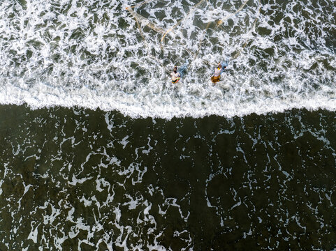 Aerial view of two fishermen standing in the sea and casting their fishing nets into the waves in Moheskhali Upazila, Chittagong Division, Bangladesh.