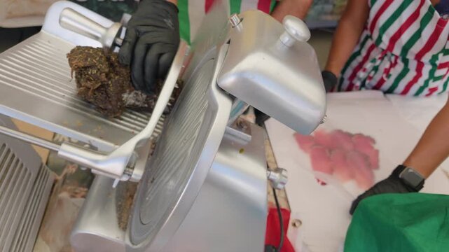 Close-up of a deli slicer blade slicing cured meat at a market stall, Cote d'Azur, France
