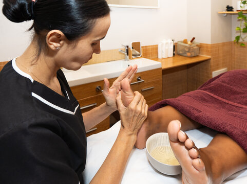 Therapist performing foot reflexology massage for client in spa