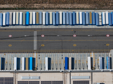 Aerial view of a massive distribution centre with rows of parked semi-trailers and loading docks at a logistics facility in Spinetta Marengo, Piedmont, Italy.