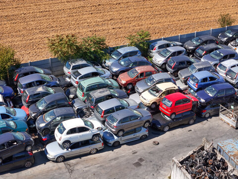 Aerial view of an end-of-life vehicles car scrapyard with rows of stacked cars and metal debris in Spinetta Marengo, Piedmont, Italy.