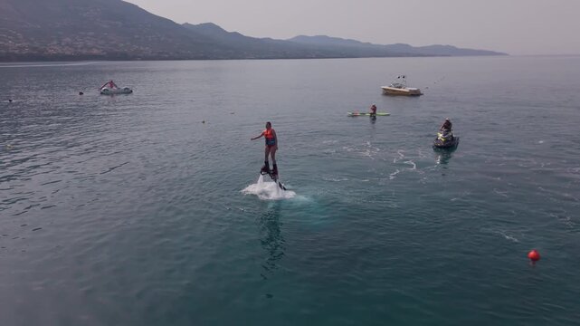 Woman Practicing Flyboarding with Repeated Takeoffs and Returns to the Water off Kalamata, Greece, Drone View