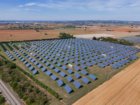 Aerial view of a solar panel system in a field with rows of photovoltaic panels under a clear blue sky in Spinetta Marengo, Piedmont, Italy.