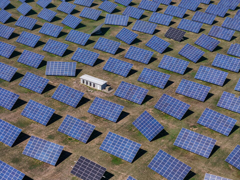Aerial view of solar panel system in a large field with rows of photovoltaic panels and a small utility building in Spinetta Marengo, Piedmont, Italy.