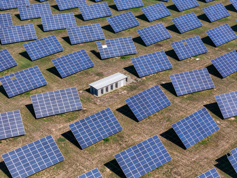 Aerial view of a large solar panel system with rows of photovoltaic modules and a small utility building situated in a field in Spinetta Marengo, Piedmont, Italy.