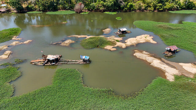 Small mining boats anchored on a river surrounded by lush green vegetation in South Kalimantan