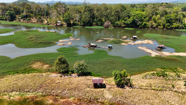 Sand mining boat working on a calm river surrounded by lush tropical vegetation in Indonesia