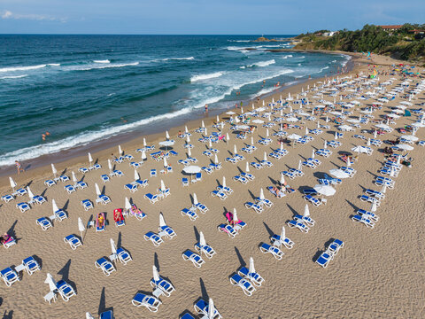 Aerial view of Central Beach Lozenets with rows of blue and white sun loungers and umbrellas on the sandy shore along the Black Sea in Lozenets, Burgas, Bulgaria.