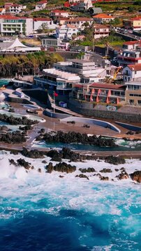 Porto Moniz natural pools area with strong ocean swell and white waves crashing along the rocky shore, Madeira, Portugal