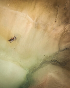 Aerial view of the Bad Eddie shipwreck resting on the sandy beach at low tide in Bunbeg, County Donegal, Ireland.
