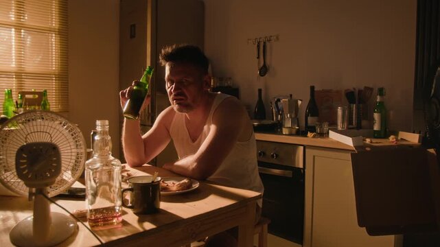 Portrait of middle aged Caucasian man drinking alcohol in kitchen, dealing with severe depression and substance abuse. Clip ideal for mental health and addiction awareness campaigns