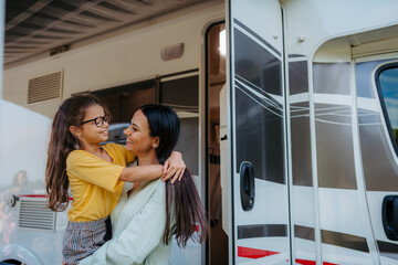 Mother with daughter enyoing family holiday with camper and caravan.