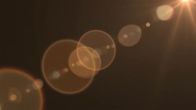 Golden lens flare effect with bright light rays and glowing optical reflections on a dark background