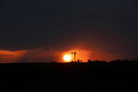 Windmill at sunset with a rain storm in the background, Pampas, Patagonia,Argentina.
