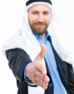 Arab businessman wearing keffiyeh offering hand for a handshake isolated on white background.