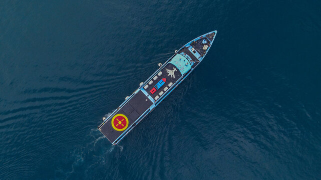 Aerial view of a passenger ferry boat cruising through the deep blue waters near Waisai Harbour in Raja Ampat, Papua Barat Daya, Indonesia.