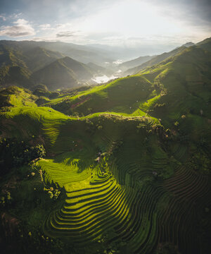 Aerial view of the lush green rice terraces at Kim Noi Viewpoint, showcasing the intricate patterns of the mountain landscape under soft sunlight in Mu Cang Chai, Lao Cai, Vietnam.