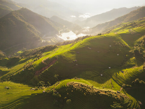 Aerial view of Kim Noi Viewpoint showcasing vibrant green terraced rice fields carved into mountain slopes under soft golden hour light in Mu Cang Chai, Lao Cai, Vietnam.