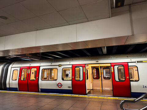 London Underground train at a station platform in London, UK with open doors and commuters boarding on the Tube
