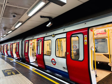 Commuters boarding a London Underground train at Victoria station on the Tube platform in UK during daily city transit and urban commute