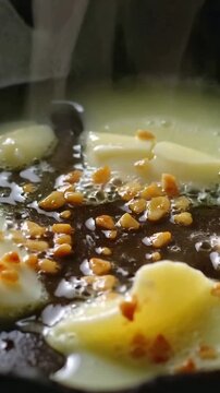 Vertical video: Heating hot pan, egg cluster sizzling, spreading on stove, oil bubbling