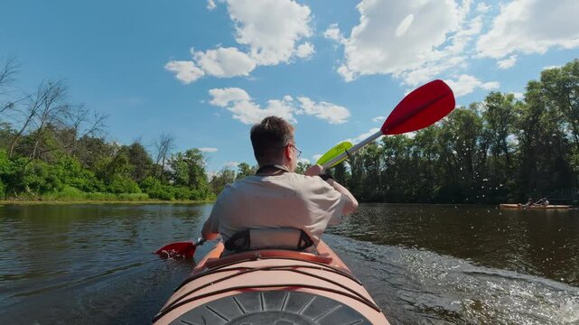 Rear view of man paddling tandem kayak on calm river for outdoor adventure concept