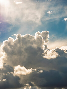 Dramatic sky with majestic cumulus clouds illuminated by bright sunlight. Heavenly sunshine peeking through storm clouds, hope and spiritual background