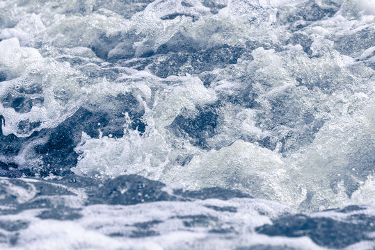 Cold swirling river current with choppy blue water and white foam.