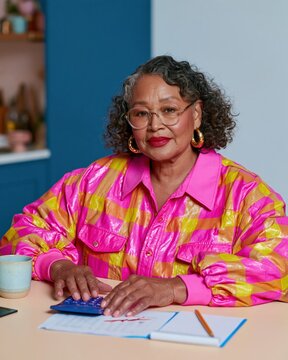 Senior Black woman calculating mortgage rates, focused and competent with a steady gaze at her kitchen table for real estate and refinancing mockups
