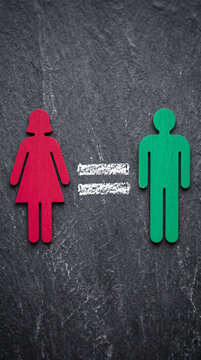Red and green gender symbols alongside an equal sign on a textured dark background, representing gender equality and inclusion concepts