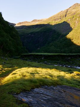 Sunbeams shining on Jotunheimen valley meadow with rocky landscape
