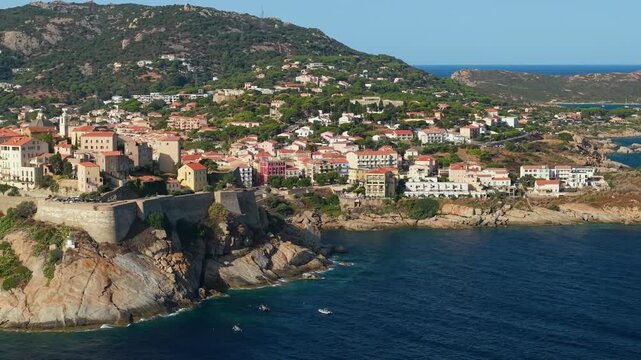 Calvi Citadel Corsica France aerial side drone flyby reveal cliff fortress town marina mountains background landscape travel destination 4k video
