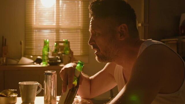 Middle aged Caucasian man suffering from alcohol addiction drinking beer from bottle. Footage fits mental health awareness campaigns and substance abuse rehab advertising
