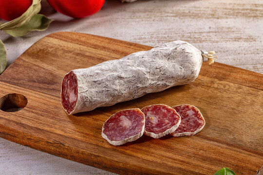 Traditional dry cured salami sausage sliced on a rustic wooden board