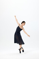 Graceful young ballerina dancing on pointe in black dress on white background © LuuNhan