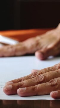 Vertical video: Reaching right hand, hands pinching and smoothing papers on desk to align