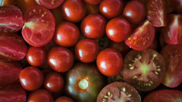 Organic multicolored tomatoes sliced into wedges with clearly visible seeds, juice and natural veins. Top view close-up. Idea of natural fresh produce and organic seasonal food