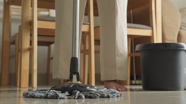 Low angle close up of a person mopping a glossy indoor floor with a flat microfiber mop