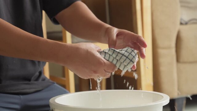 Person wringing a cleaning rag during household cleaning