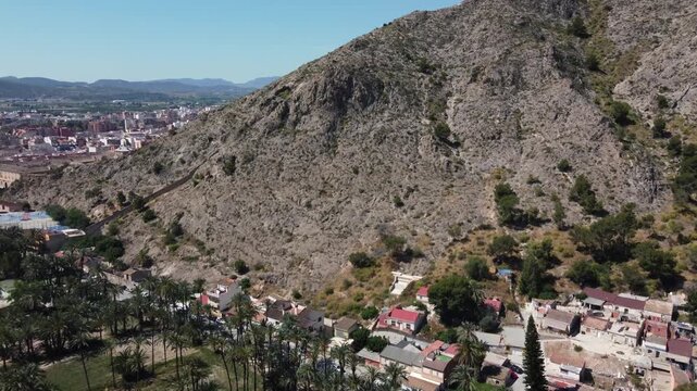 Aerial view flying over the historic San Anton Hermitage toward the scenic Orihuela mountain range in Spain. High-resolution drone stock footage.