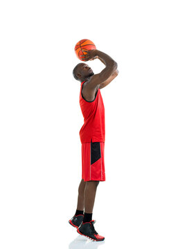 Full length portrait of male basketball player shooting ball isolated on white background.