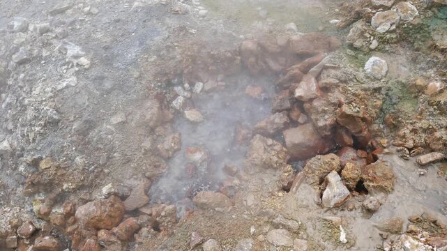 Geothermal springs in Tuscany, Italy, with mineral-rich rocks, steaming ground, and vivid green thermal deposits, showcasing volcanic activity, natural energy, and unusual landscape formations