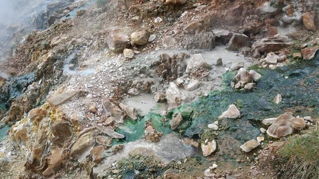 Geothermal springs in Tuscany, Italy, with mineral-rich rocks, steaming ground, and vivid green thermal deposits, showcasing volcanic activity, natural energy, and unusual landscape formations