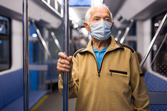 Senior man in mask inside subway car