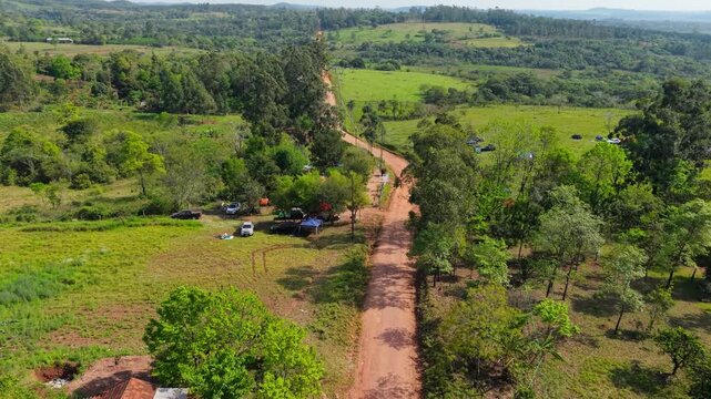 Dirt rally road winding through green countryside near Nueva Alborada, Paraguay, aerial establishing medium