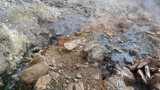 Geothermal springs in Tuscany, Italy, with mineral-rich rocks, steaming ground, and vivid green thermal deposits, showcasing volcanic activity, natural energy, and unusual landscape formations