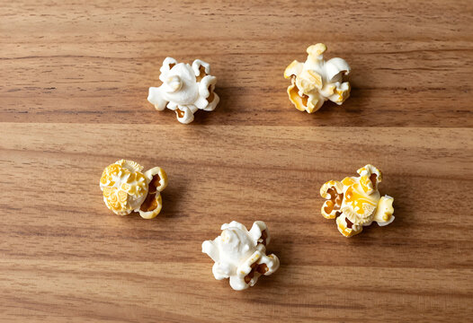 Snack time and cinema entertainment, fresh popcorn kernels scattered on a wooden table for movie night and casual food lifestyle photography