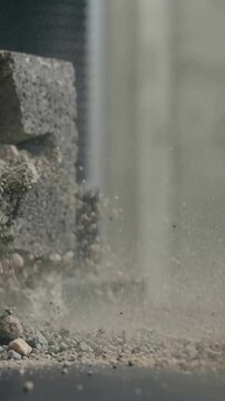 Vertical video: Hitting offscreen causing cinderblock cracking, throwing stones and dust at lab